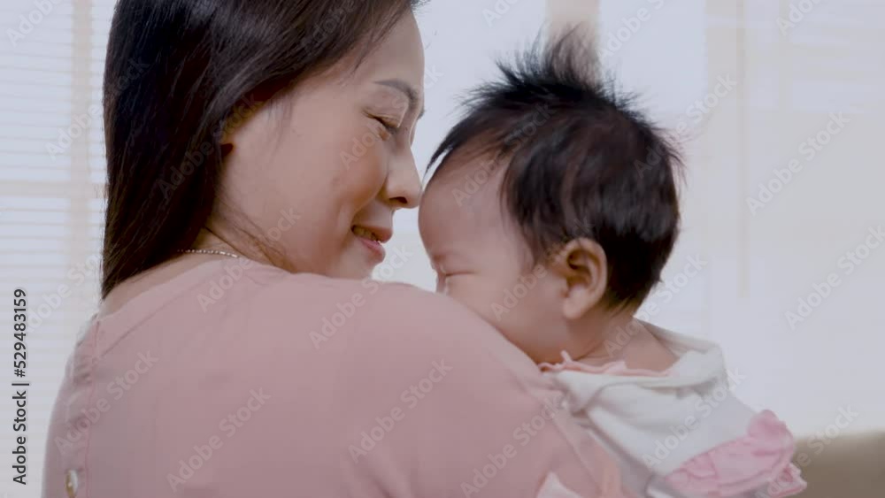 4K, Close Up is a 3-month-old newborn Asian girl who her mother is holding. A single mother is holding her newborn baby by soothing her to sleep. in the bedroom of the house. Family and Healthy. 4K, Close Up is a 3-month-old newborn Asian girl who her mother is holding. A single mother is holding her newborn baby by soothing her to sleep. in the bedroom of the house. Family and Healthy.