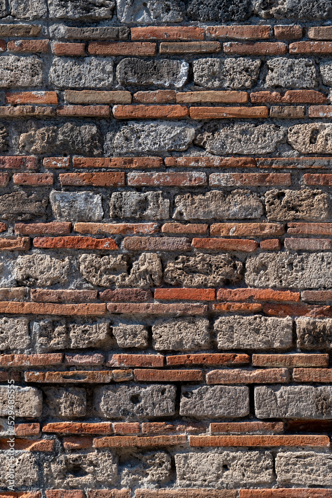 Brick layers of a facade wall in Pompeii. Building made by roman masonry craftsmen 2000 years ago. Historic excavations are a major sight and world heritage in Campania near Naples and mount Vesuvius.
