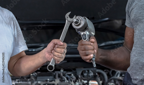 Two car mechanic hands holding tools working with car problem in auto repair service
