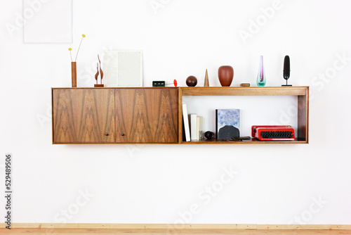 a vintage 60s mid century highboard sideboard made out of rosewood in denmark hanging on the wall in the living room danish design decorated furnished with expensive vases on top of it and books  photo