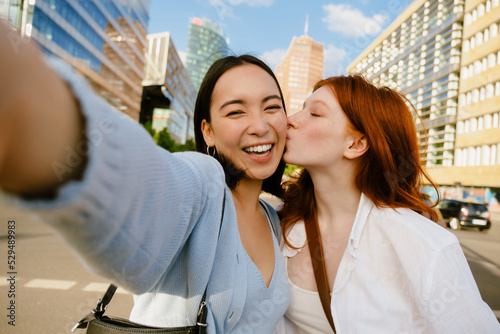 Selfie of young happy asian girl with beautiful redhead friend photo