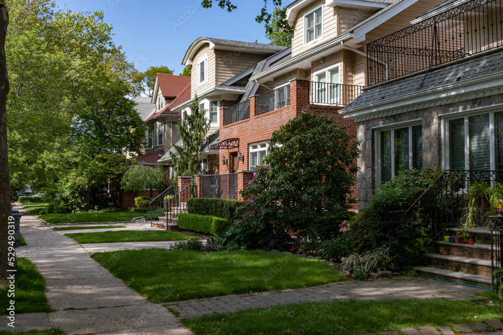 Row of Beautiful Neighborhood Homes with Green Grass along a Sidewalk in Midwood Brooklyn of New York City