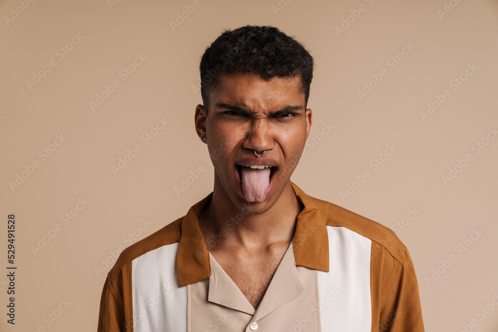 Young handsome frowning african man showing his tongue