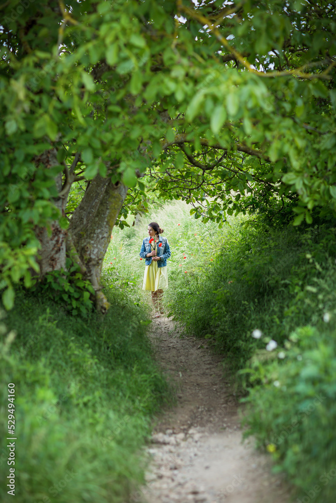 Woman in yellow dress gathering poppy and wildflowers, walking in summer meadow. Atmospheric authentic moment. Rural slow life in countryside Woman in yellow dress gathering poppy and wildflowers, walking in summer meadow. Atmospheric authentic moment. Rural slow life in countryside