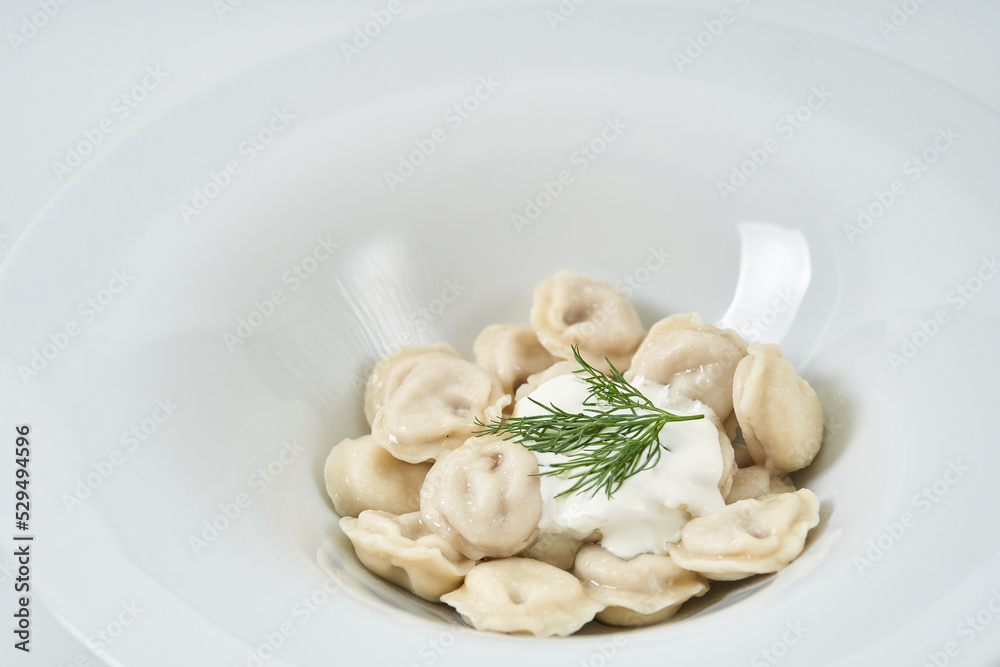 dumplings with sour cream with herbs on a white plate dumplings with sour cream with herbs on a white plate