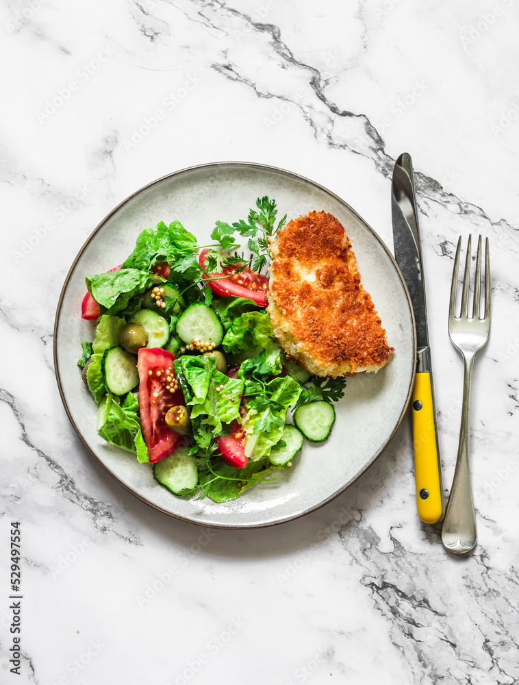 Fresh vegetable salad and fried haloumi in breadcrumbs - a delicious vegetarian lunch on a light background, top view