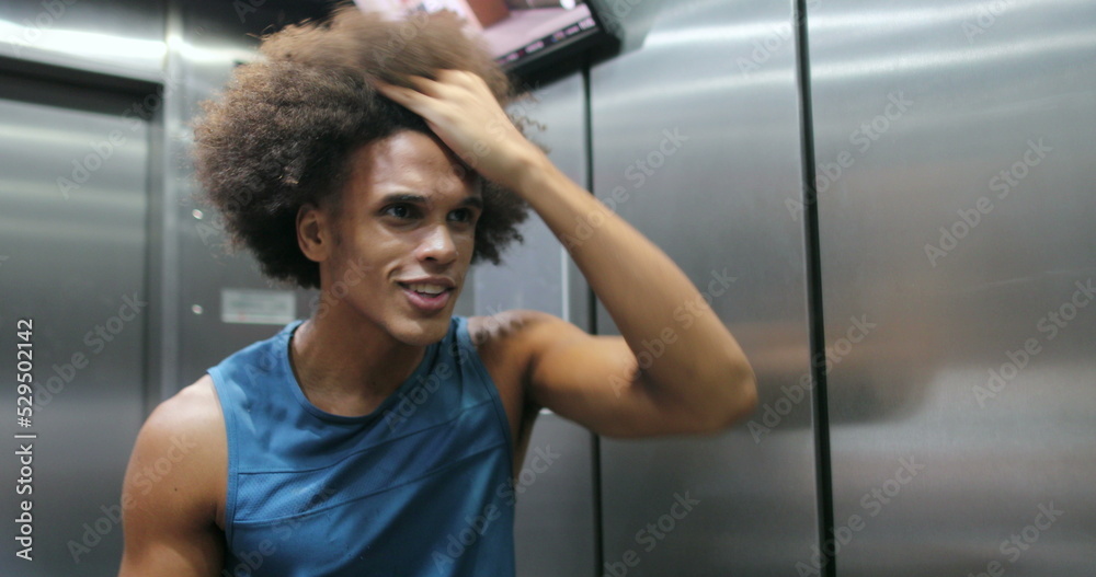 African man examining himself in front of elevator mirror African man examining himself in front of elevator mirror