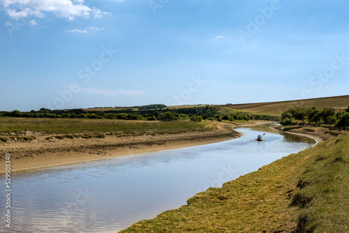 Fototapeta Naklejka Na Ścianę i Meble -  People kayaking on the river Cuckmere on a summer afternoon, East Sussex, England