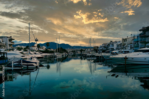 Empuriabrava spanish town in view of main water channel with boats at dusk. Landscape of the catalan town in the Costa Brava region known for its canals and marina © davide bonaldo