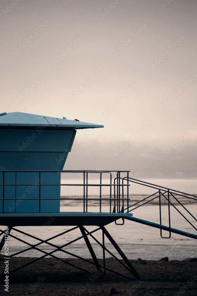 Light blue lifeguard tower on a beach in California, on a cloudy and foggy day.