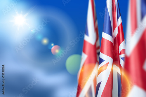 National flags of United Kingdom on a flagpole on blue sky background. Lowered UK flags. Background with place for your text. photo