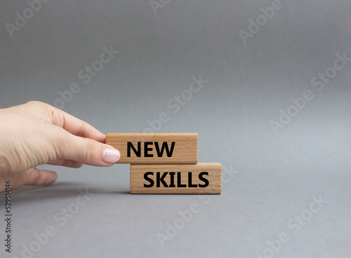 New skills symbol. Wooden blocks with words New skills. Beautiful grey background. Businessman hand. Business and New skills concept. Copy space.
