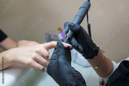 Beauty salon, manicure. Professional hardware manicure using an electric machine in a beauty salon.