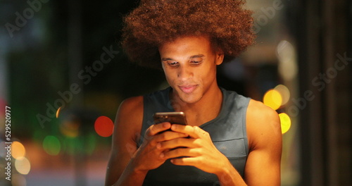 Handsome african man typing on cellphone device at night
