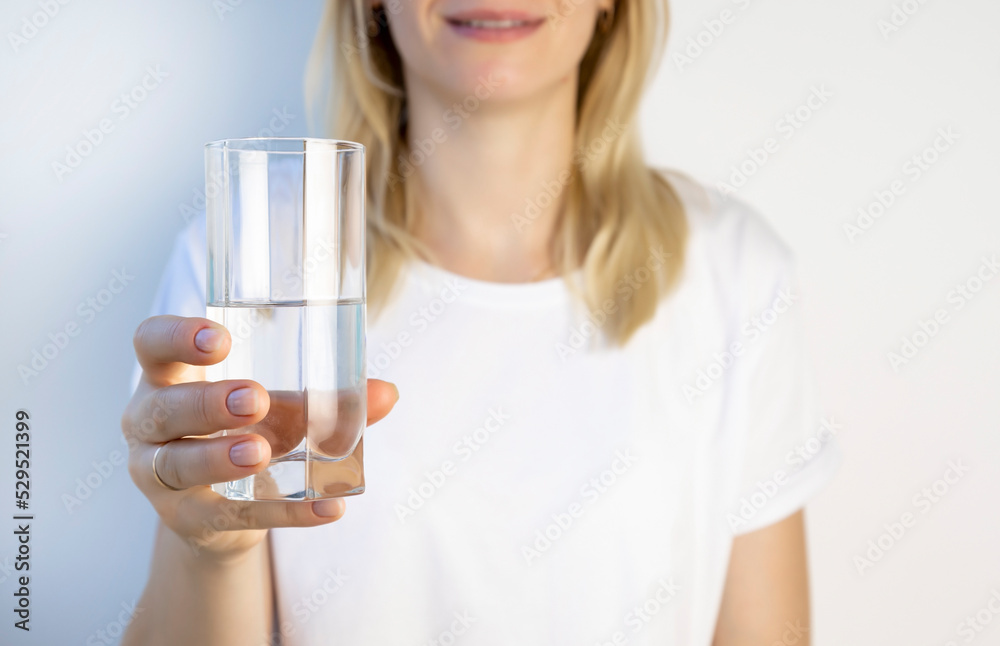 The concept of maintaining water balance in the body. The girl holds a glass of water in front of her. The concept of maintaining water balance in the body. The girl holds a glass of water in front of her.