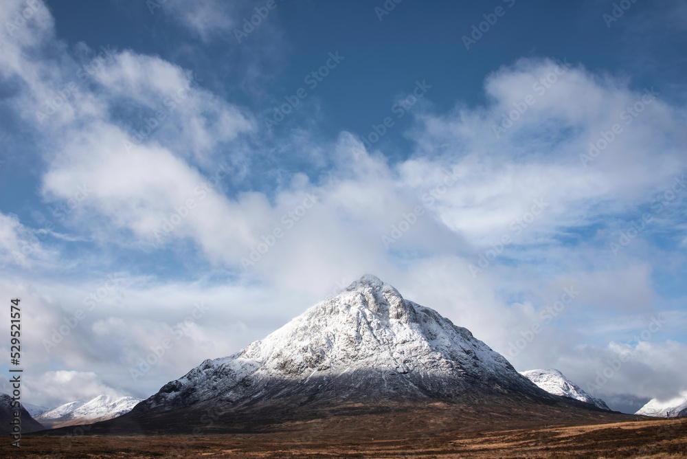 Beautiful iconic landscape Winter image of Stob Dearg Buachaille Etive Mor mountain in Scottish Highlands againstd vibrant blue sky