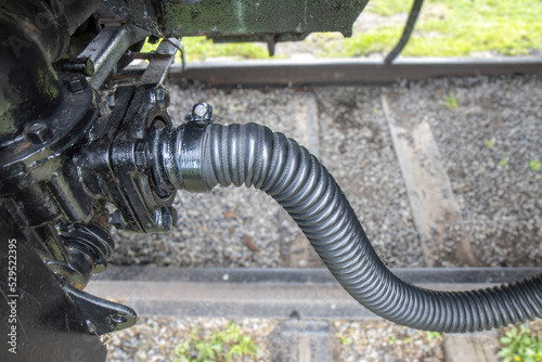 Air hose for train wheel brakes coupled to a connector on a rail car, outdoors, daylight, nobody