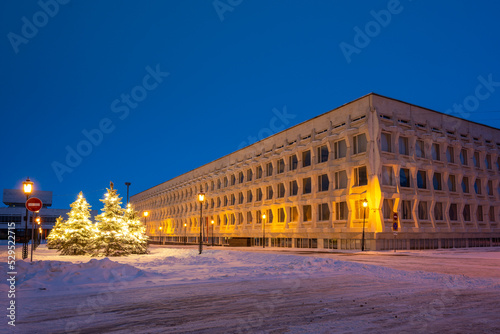 Snow-covered Christmas trees decorated with garlands  street lamps and Ulyanovsk State Pedagogical University.