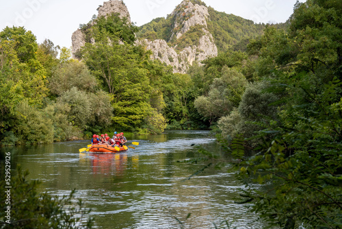 Group of tourists taking rafting tour on the Cetina river, listening to the information from the instructor in the dinghy