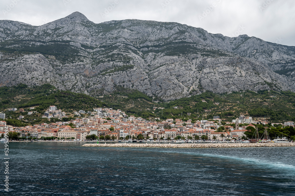 Sailing out of Makarska town port, placed under high slopes and cliffs of Biokovo mountain, Croatia