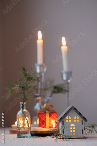 Christmas tree and a candlestick in the form of a house, soft selective focus. a cozy miniature layout of the house. decorations for Christmas with candles, confetti and ribbons, holidays. give gifts
