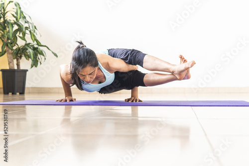 Mature woman practicing yoga, Astavakrasana or eight angle posture