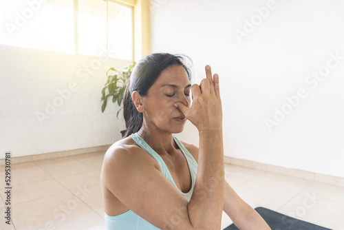 Canvas Print Close-up of a Latin woman practicing alternate nostril breathing next to a windo
