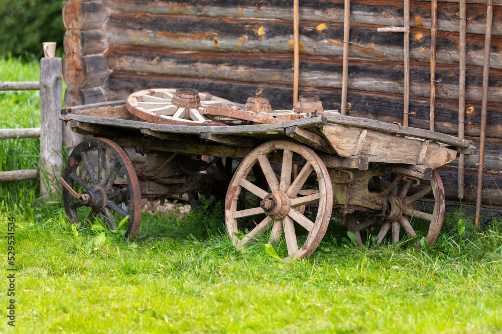 Old wooden wagon stands on green grass