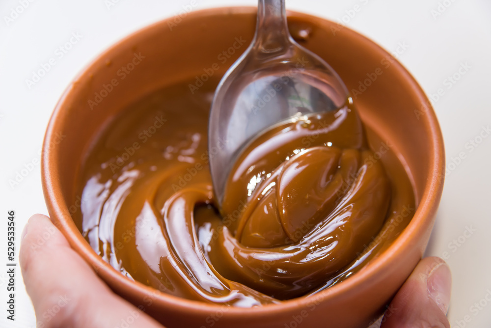 close up of spoon stirring dulce de leche close up of spoon stirring dulce de leche