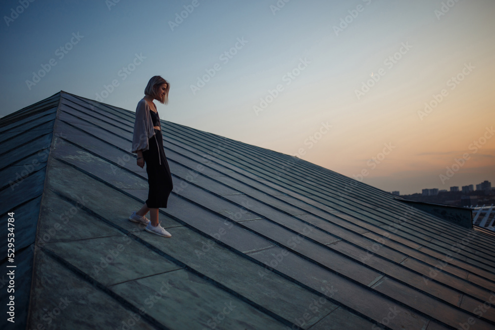 Photo shoot on the roof. Young woman posing in the roof, amazing view of city. People, lifestyle, relaxation concept.