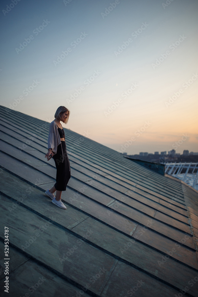 Photo shoot on the roof. Young woman posing in the roof, amazing view of city. People, lifestyle, relaxation concept.
