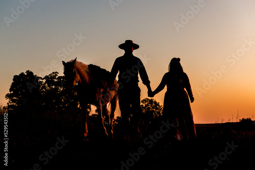 Silhouette of horse and gaucho family at sunset in South Brazil