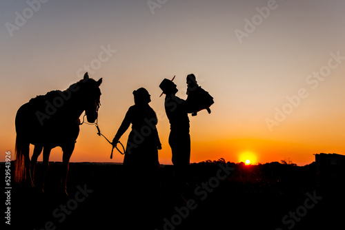 Silhouette of horse and gaucho family at sunset in the countryside. photo