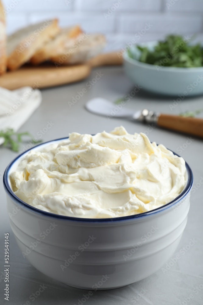 Bowl of tasty cream cheese on grey table Bowl of tasty cream cheese on grey table