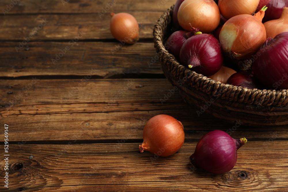 Onion bulbs and basket on wooden table. Space for text Onion bulbs and basket on wooden table. Space for text