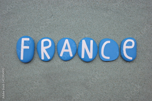 France, country name composed with blue colored stone letters over green sand