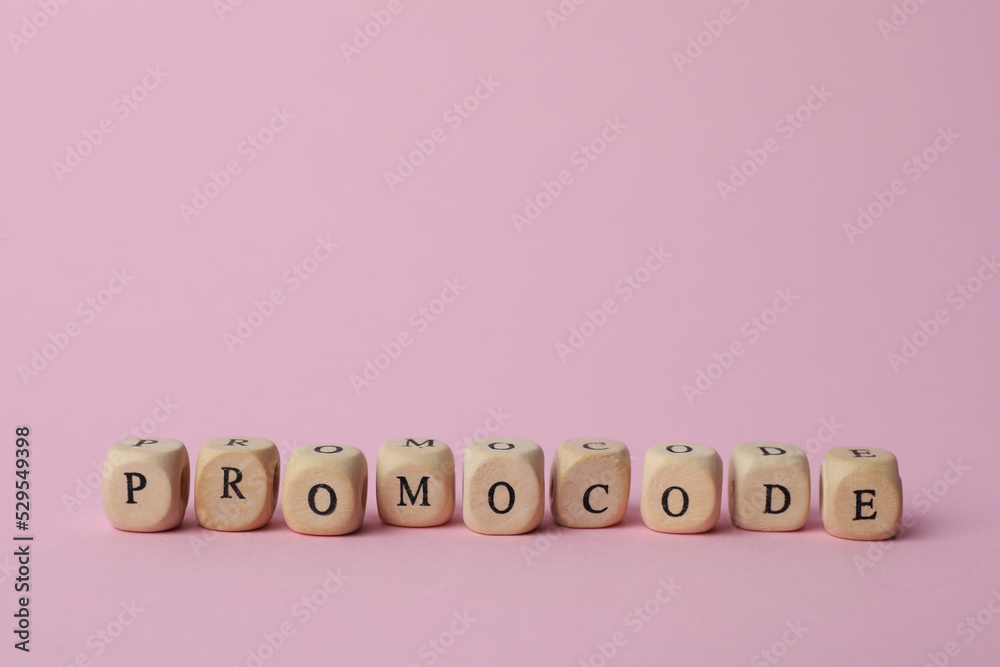 Word Promocode made of wooden cubes with letters on pink background, space for text Word Promocode made of wooden cubes with letters on pink background, space for text
