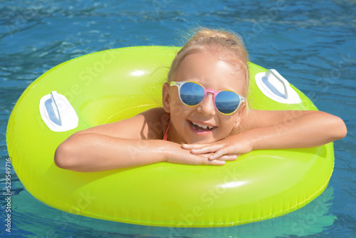 Little girl with inflatable ring in sea on sunny day