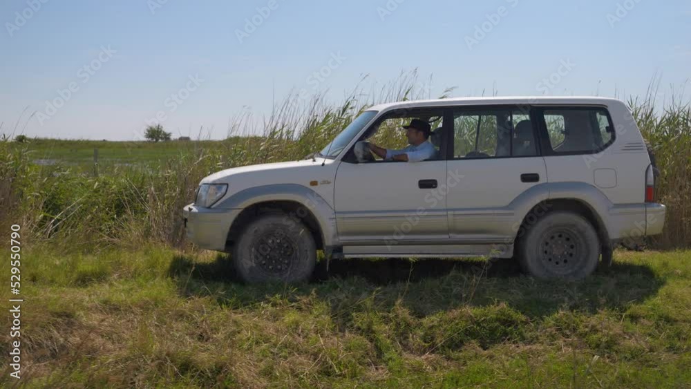 Cowboy driving his 4x4 jeep through the the rural grass in a farm field. Cowboy driving his 4x4 jeep through the the rural grass in a farm field.