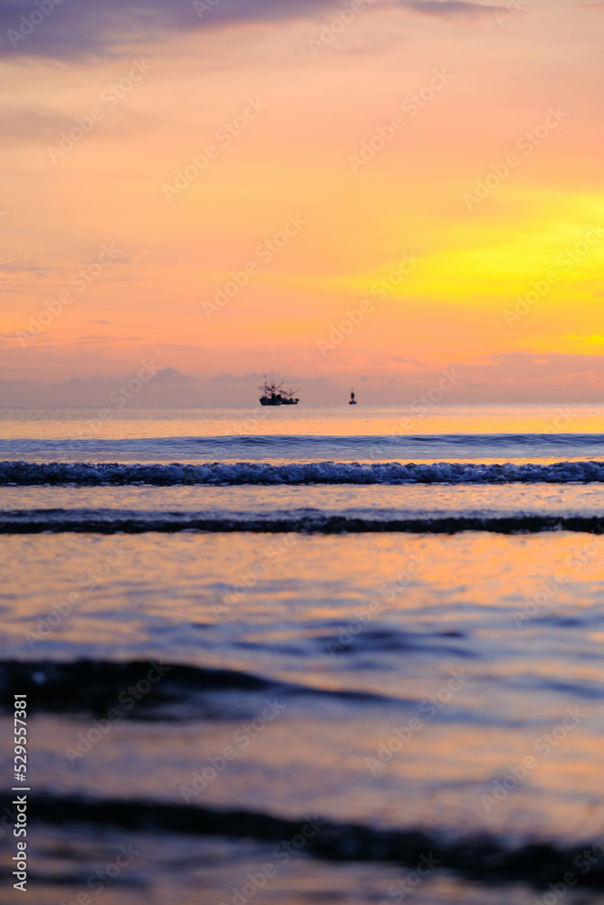Beautiful sunset view on the beach. Colorful sea beach sunset with golden light reflected on the water surface and soft waves. Summer vacation and travel concept.