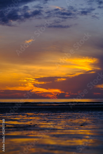 Beautiful sunset view on the beach. Colorful sea beach sunset with golden light reflected on the water surface and soft waves. Summer vacation and travel concept.