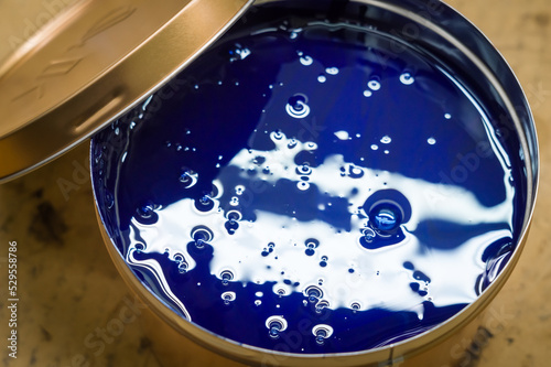 A can of blue polygraph offset paint for the printing press. Special UV ink for printing. Cyan color. Open new can of blue paint. Selective focus