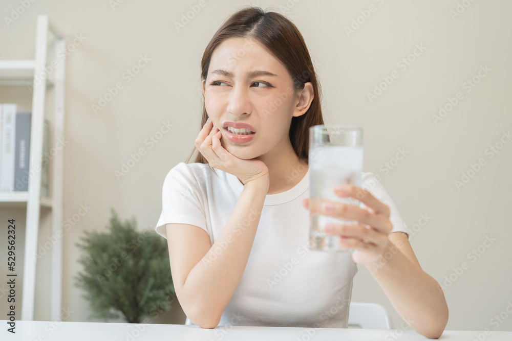 Suffering from toothache, asian young woman, girl touch cheek, face expression ache or feel pain, sensitive molar teeth, hand holding glass of water with ice, inflammation when drink cold, healthcare. Suffering from toothache, asian young woman, girl touch cheek, face expression ache or feel pain, sensitive molar teeth, hand holding glass of water with ice, inflammation when drink cold, healthcare.