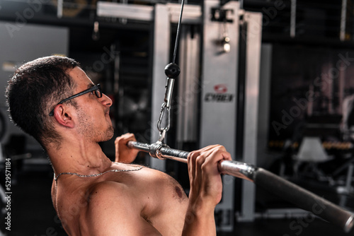 High quality photography. Man in the gym doing chest training pulling cable with weight on a pulley. Hispanic man training with crossover.