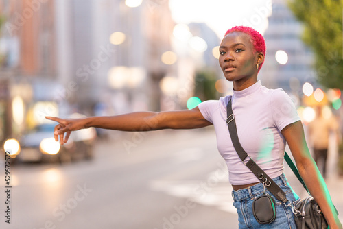 African woman with short pink hair hairstyle hailing a taxi