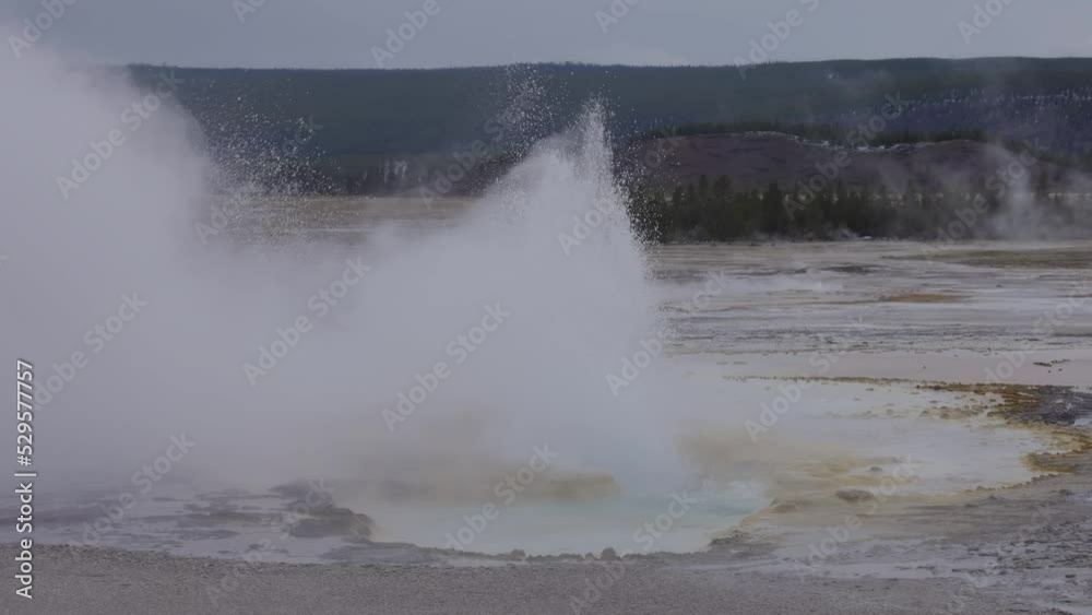 Hot spring Geyser with colorful water in American Landscape. Cloudy Sky. Yellowstone National Park, Wyoming, United States. Nature Background. Slow Motion Hot spring Geyser with colorful water in American Landscape. Cloudy Sky. Yellowstone National Park, Wyoming, United States. Nature Background. Slow Motion