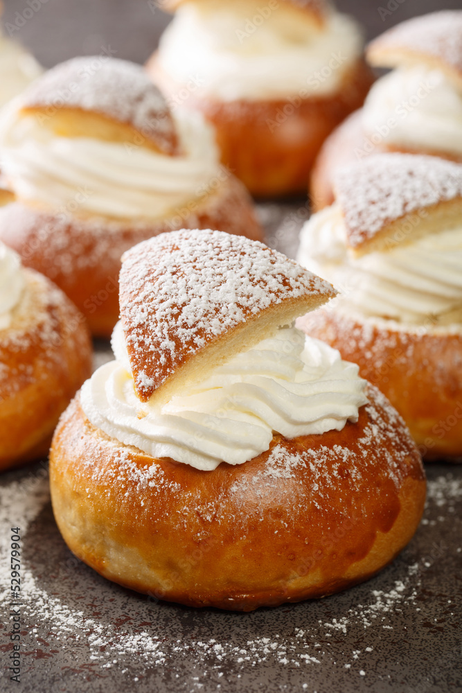 Traditional winter sweet: Semla semlor or fastlagsbulle flavored with cardamom, filled with almond paste and whipped cream closeup on the table. Vertical