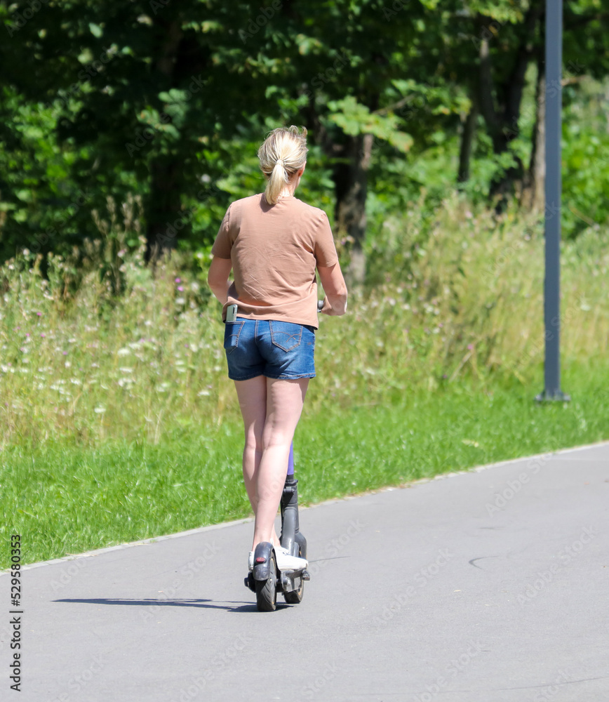 Fototapeta premium A girl rides a scooter along the road