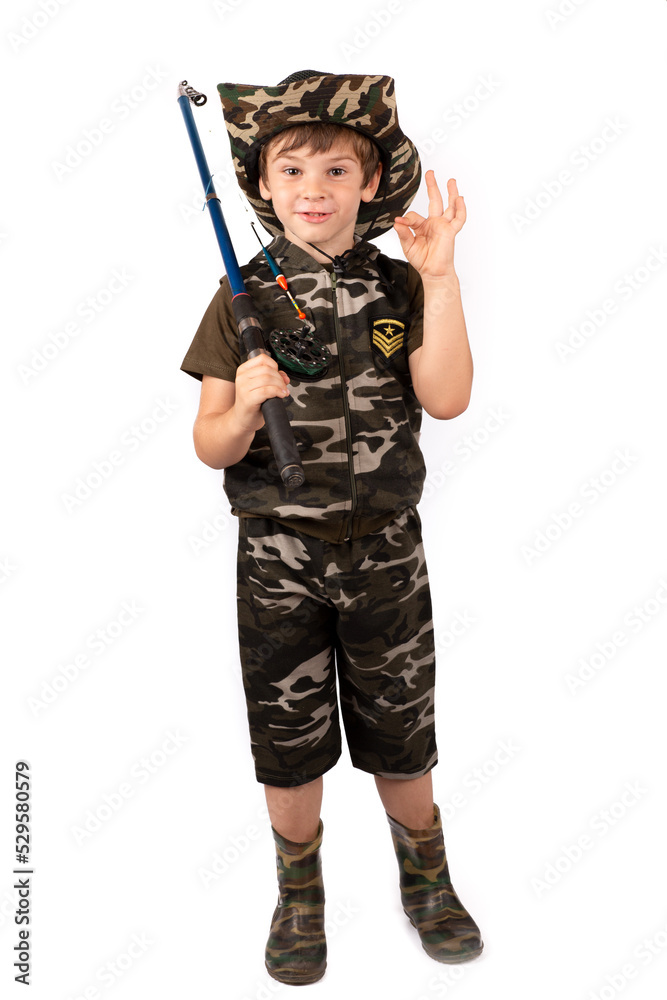 A fisherman boy in a fishing suit and hat with a fishing rod shows ok. Fishing A fisherman boy in a fishing suit and hat with a fishing rod shows ok. Fishing