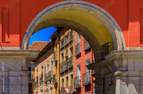 Gate to the Plaza Mayor surrounded by cafes and restaurants along the arches with a view to Calle de Felipe III in Madrid, Spain